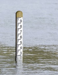 26570883 - flood level depth marker post with rain falling into the surrounding water